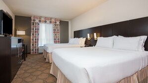 A hotel room with two beds, a TV, a desk, and a lamp.