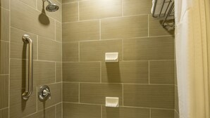 A bathroom with a bathtub, a showerhead, and a handrail.