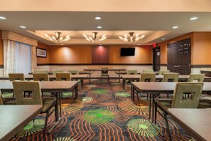 A conference room with tables and chairs, a patterned carpet, recessed lighting, and a television on the wall. - Holiday Inn Express Hotel & Suites Hobbs by IHG (Hobbs)