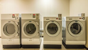 A row of four Wascomat front-loading washing machines in a commercial setting.