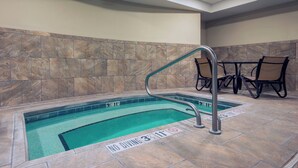An indoor swimming pool with a no diving sign, a metal pool ladder, and a tiled wall.