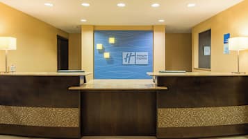 Un mostrador de recepción con un letrero de Holiday Inn Express, dos lámparas y un letrero de registro de entrada y salida.