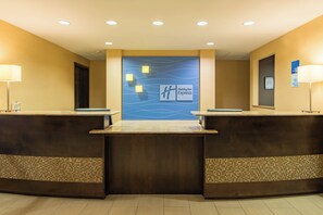 A reception desk with a Holiday Inn Express sign, two lamps, and a check-in/out sign. - Holiday Inn Express Hotel & Suites Hobbs by IHG (Hobbs)