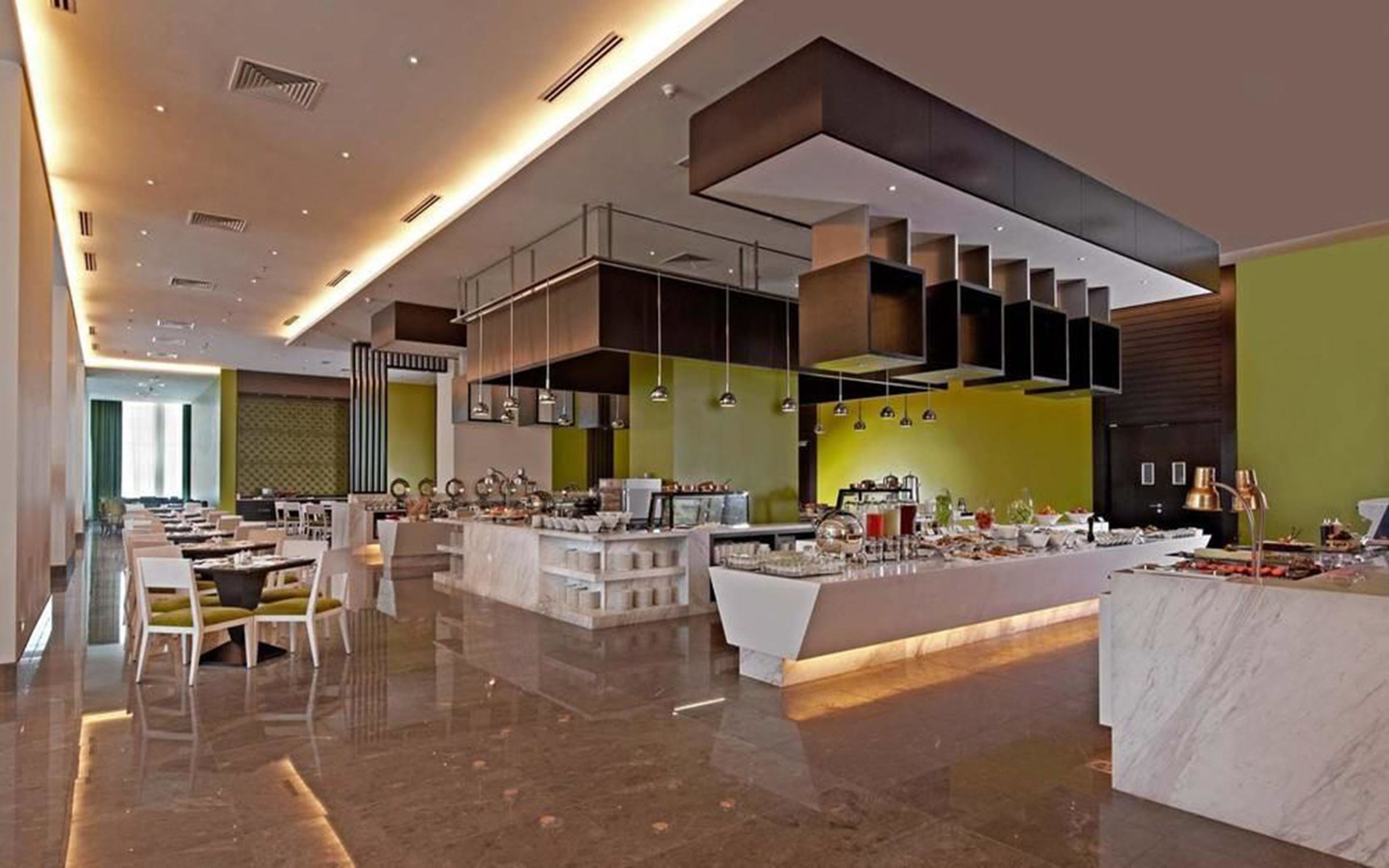A modern hotel lobby with a central bar area, seating arrangements, and a polished marble floor.