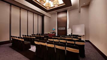 A conference room with rows of chairs, a whiteboard, and a table with a red cloth.