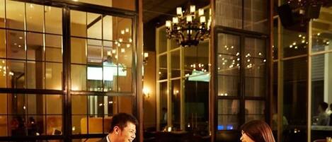 A couple dining at a restaurant with large windows and chandeliers.