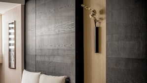 A modern room with a large bed, a dark textured wall, and a vase with flowers. - Suye Hotel (Taichung)