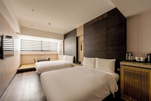A hotel room with two beds, a desk, a minibar, and a window with blinds. - Suye Hotel (Taichung)