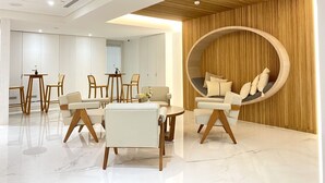 A modern interior with a circular seating area, a dining table with chairs, and a sofa. - Suye Hotel (Taichung)
