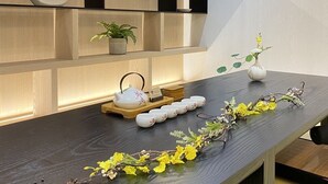 A modern interior with a wooden table, shelves with decorative items, and a minimalist design. - Suye Hotel (Taichung)