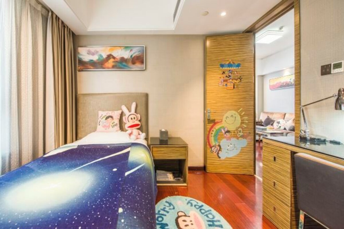 A hotel room with a bed, a desk, a mirror, and a wall with a painting.