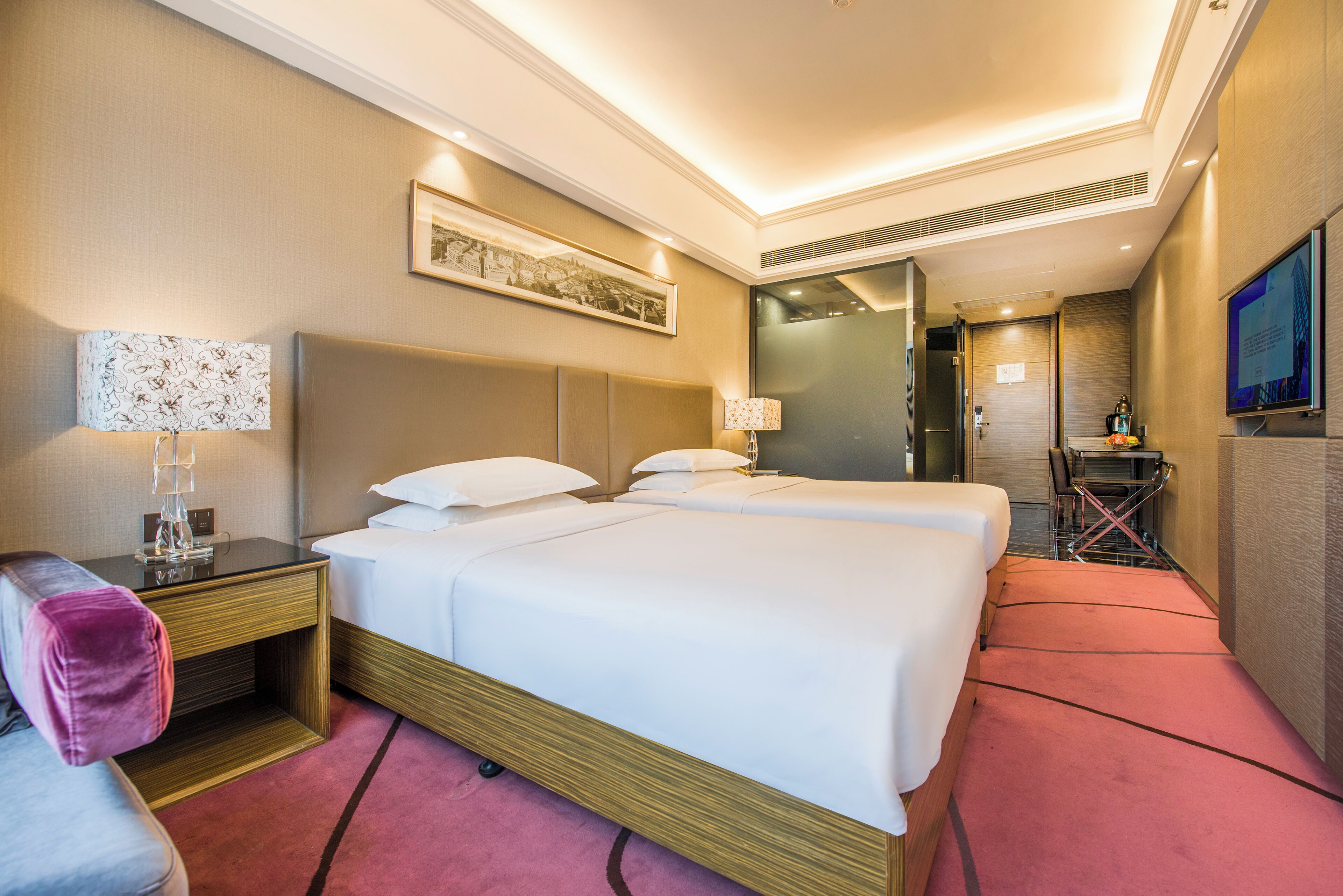 A hotel room with two beds, a desk, a chair, and a TV.