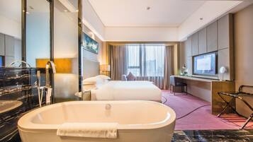 Une chambre d’hôtel avec une grande baignoire, un lit, un bureau et un téléviseur.