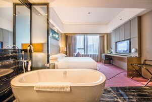 Une chambre d’hôtel avec une grande baignoire, un lit, un bureau et un téléviseur.