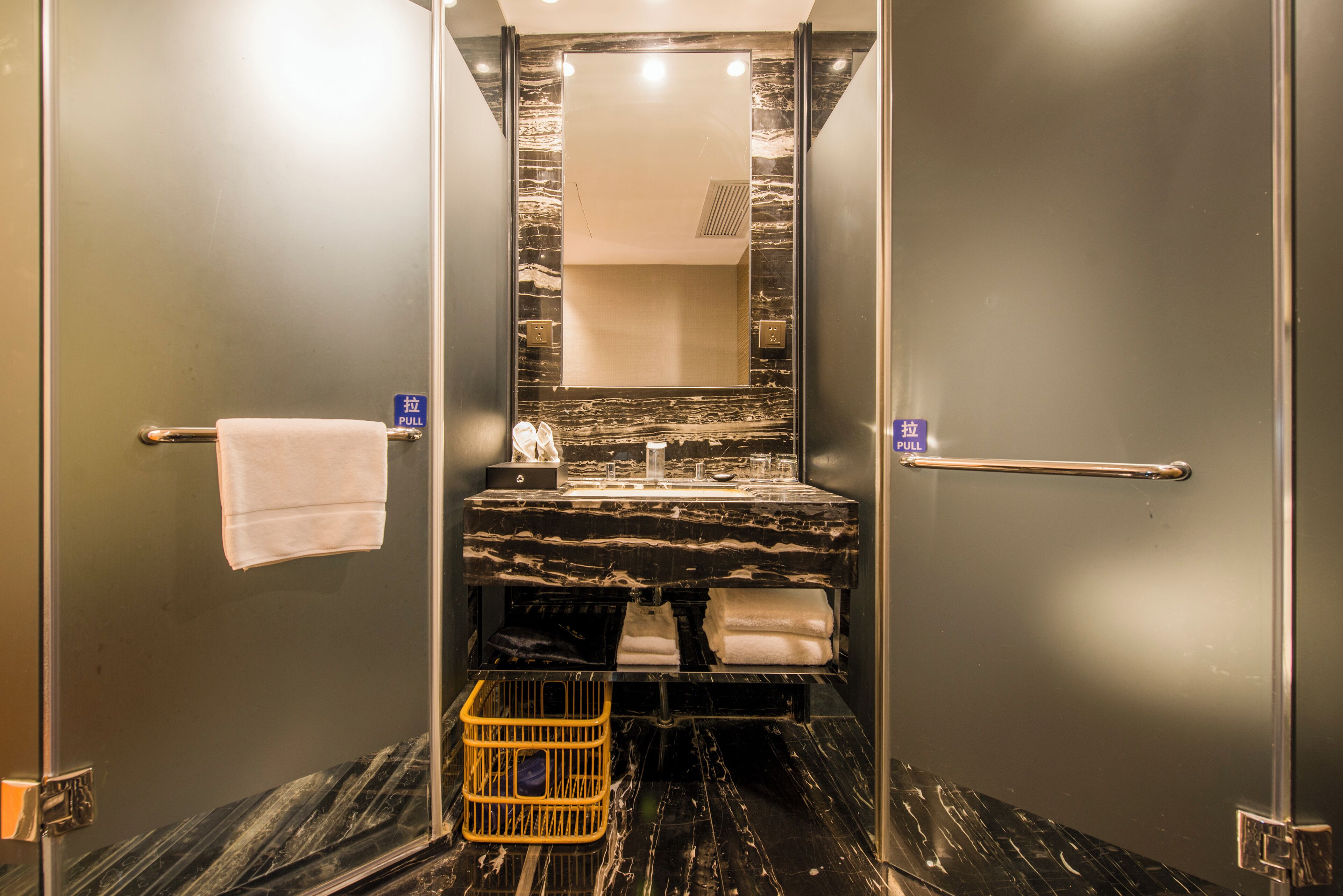 A modern bathroom with a marble countertop, a sink, a mirror, and a towel rack.