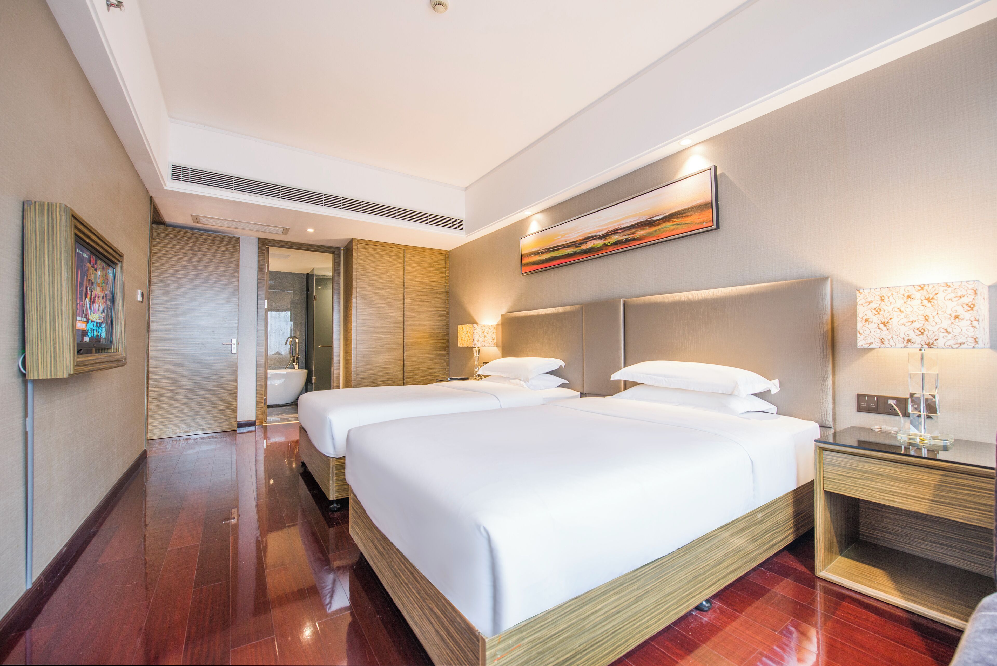 Habitación de hotel con dos camas, un baño y un pasillo.
