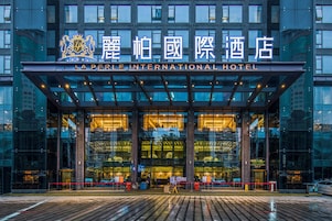 Fachada moderna de cristal y señalización iluminada del Hotel La Perle International.