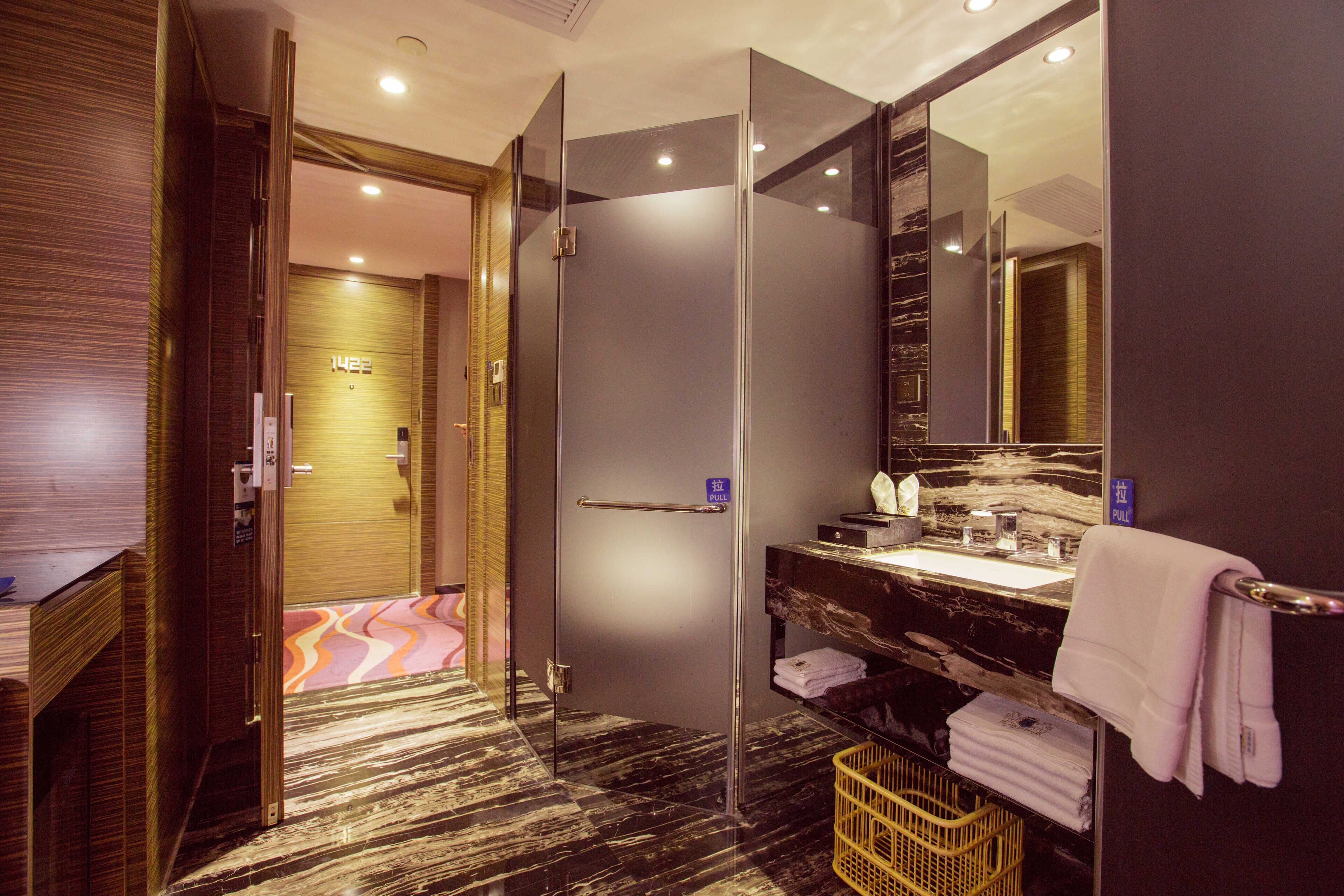A modern bathroom with a glass shower enclosure, a marble countertop, and a large mirror.