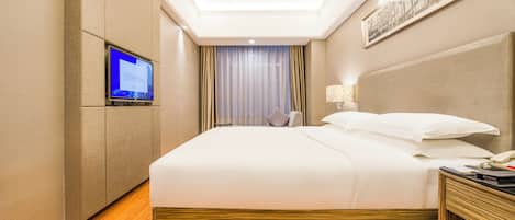 Une chambre d’hôtel avec un grand lit, un téléviseur fixé au mur, une table de chevet et une fenêtre avec des rideaux.