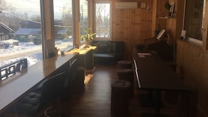 Ein gemütliches Blockhaus-Interieur mit Holzwänden, großen Fenstern, einem Holztisch und einer Bank.