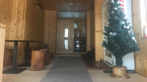 Ein Holzinnenraum mit Weihnachtsbaum, einer Rezeption und einer Tür zu einem anderen Raum.