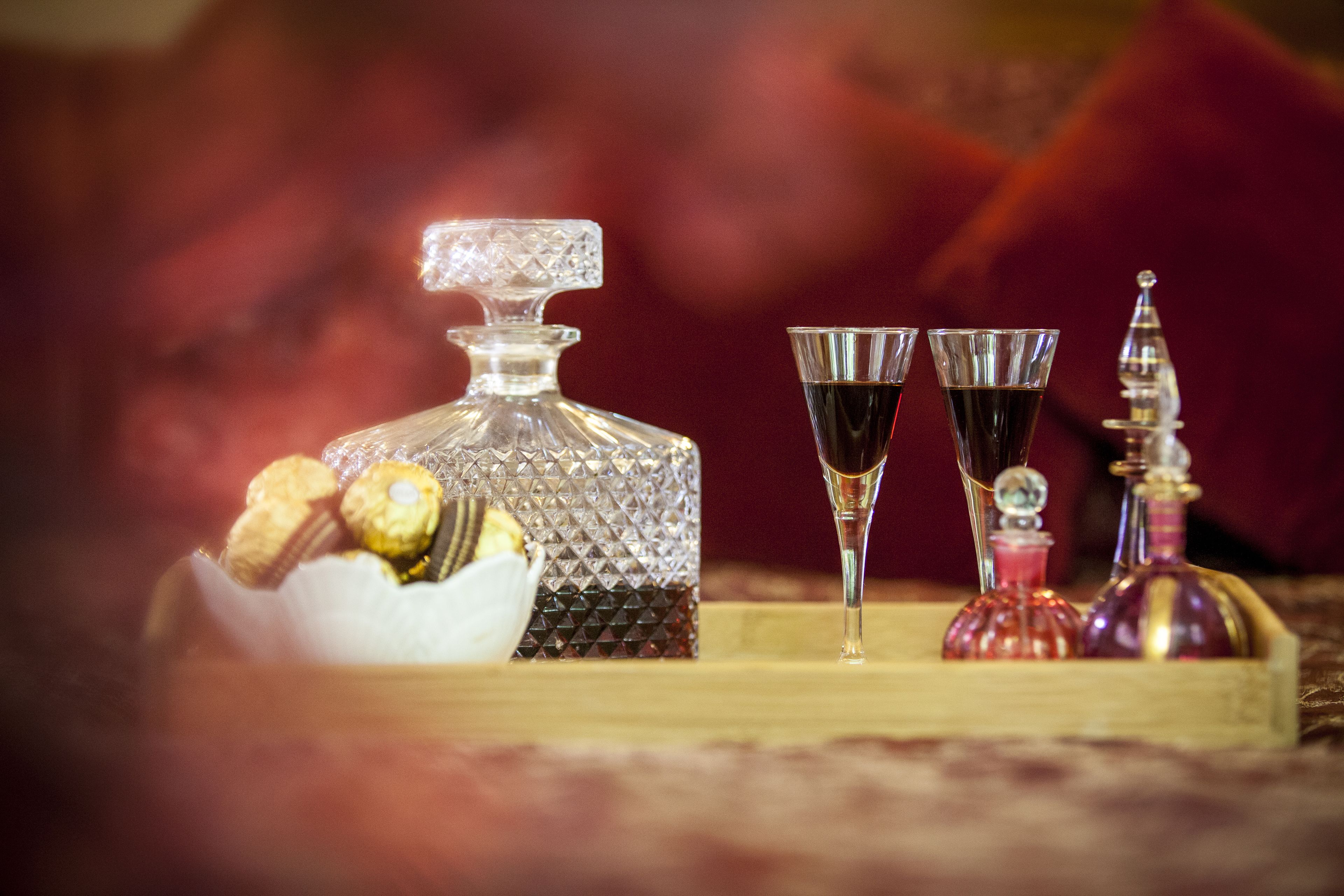 A decanter, two glasses, and a bottle of wine on a wooden tray.