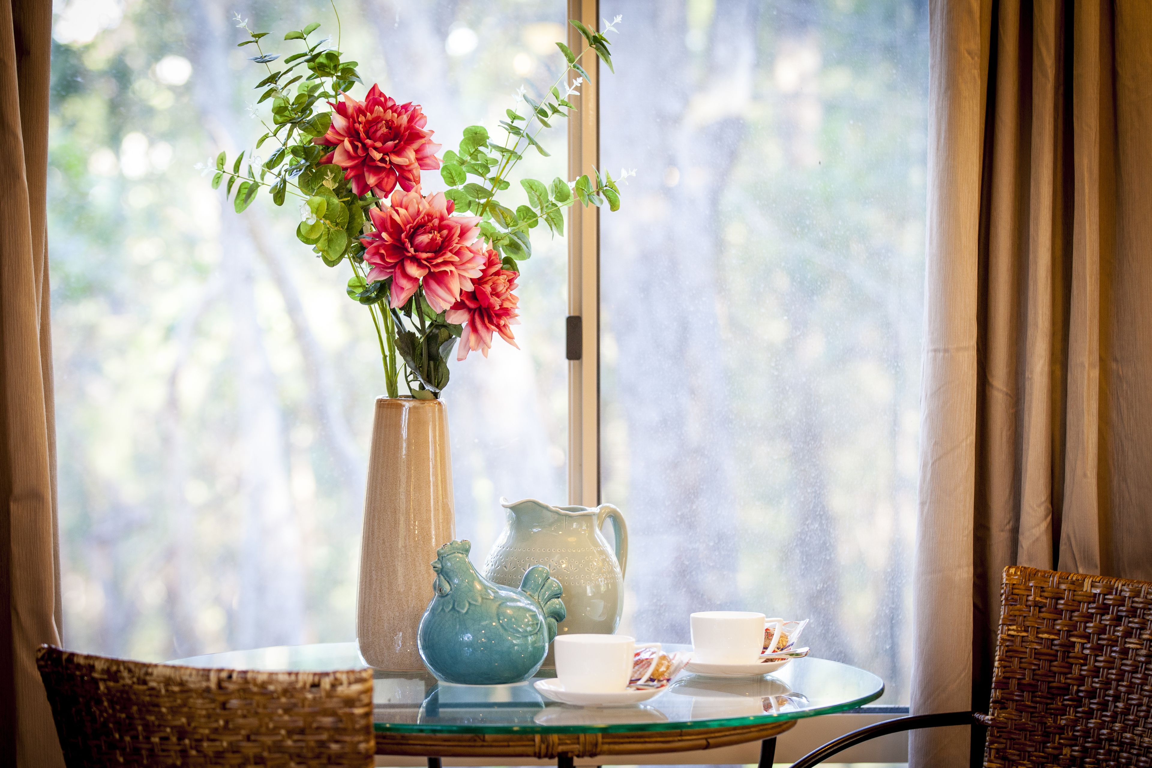 A table with a vase of flowers, a pitcher, and a cup and saucer.