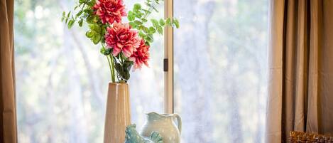 A table with a vase of flowers, a pitcher, and a cup and saucer.