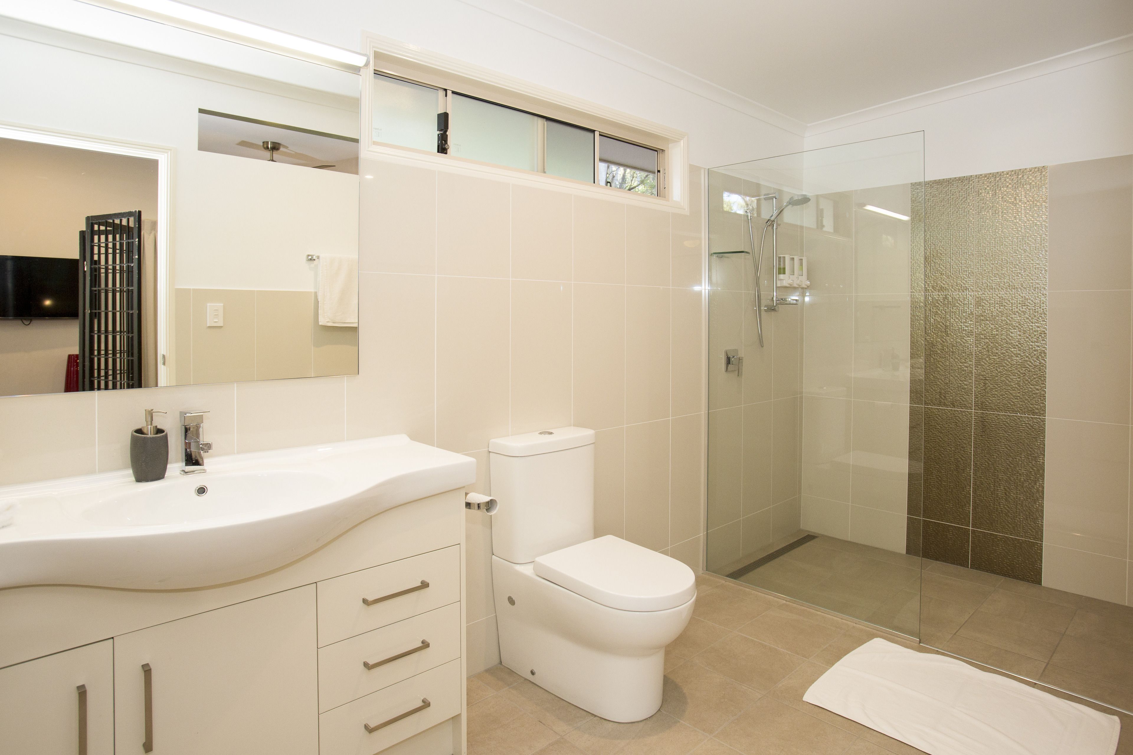 A modern bathroom with a white sink, toilet, and glass-enclosed shower.