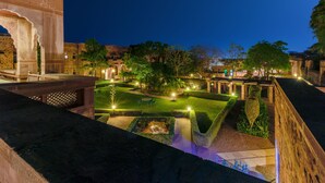 A courtyard with a fountain, a large archway, and well-maintained gardens at night. - Bijolai Palace - A Inde Hotel Jodhpur (Jodhpur)