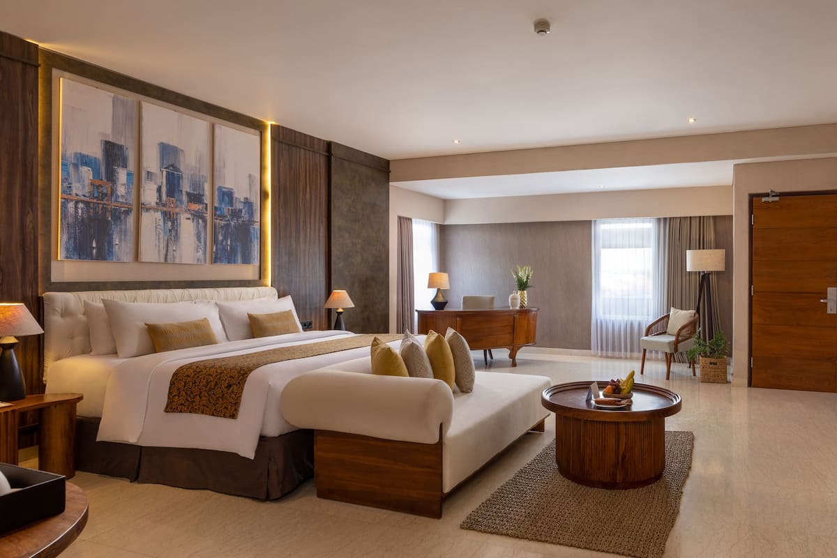 A hotel room with a large bed, a desk, a chair, and a coffee table.