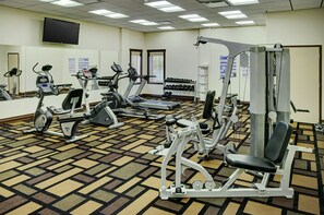 Ein Fitnessraum mit Laufbändern, Crosstrainern und Gewichten.