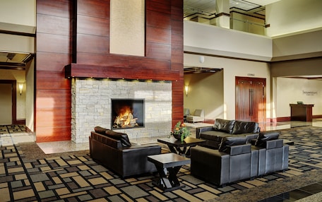 A lobby with a stone fireplace, leather sofas, and a patterned carpet.