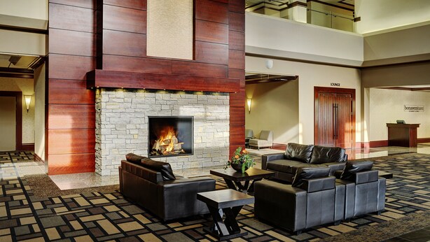 A lobby with a stone fireplace, leather sofas, and a patterned carpet. - Chateau Nova Yellowhead (Edmonton)