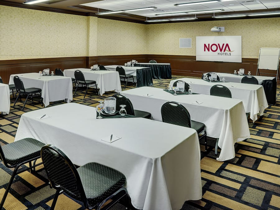 Un salón de conferencias con varias mesas y sillas, una pizarra y un letrero de NOVA Hotels.