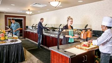 A buffet setup with multiple food stations, a serving counter, and a variety of dishes displayed on a table.