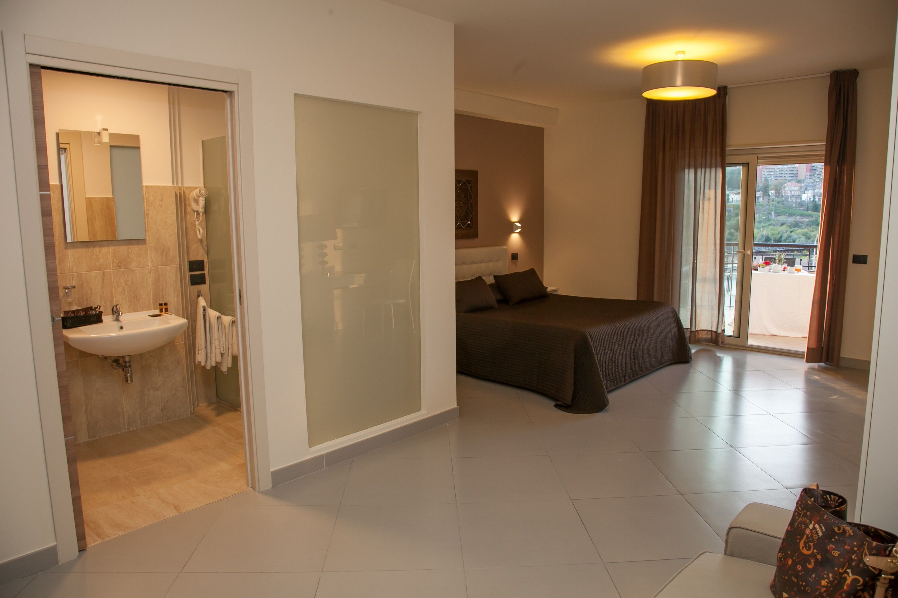 Camera d'albergo con bagno, un letto, una poltrona e vista esterna.