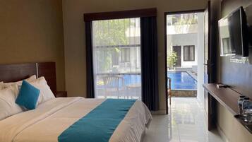 A hotel room with a bed, a TV, and a view of a swimming pool.