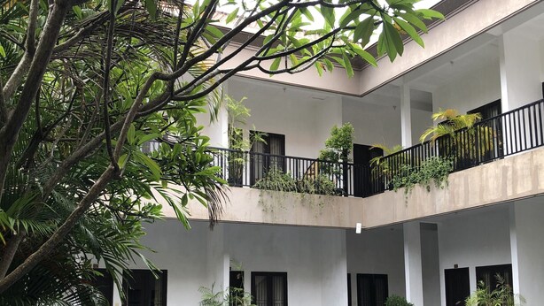 A multi-level building with a central pool, surrounded by potted plants and outdoor seating. - Seminyak Point Guest House (Seminyak)