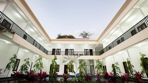 A multi-level atrium with glass railings, potted plants, and a central open space. - Seminyak Point Guest House (Seminyak)