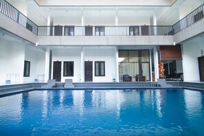 Una amplia piscina interior con balcón y zona de estar.
