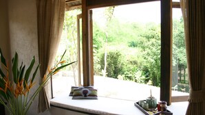 A window with a view of greenery, a plant, and a tray with items on a ledge.
