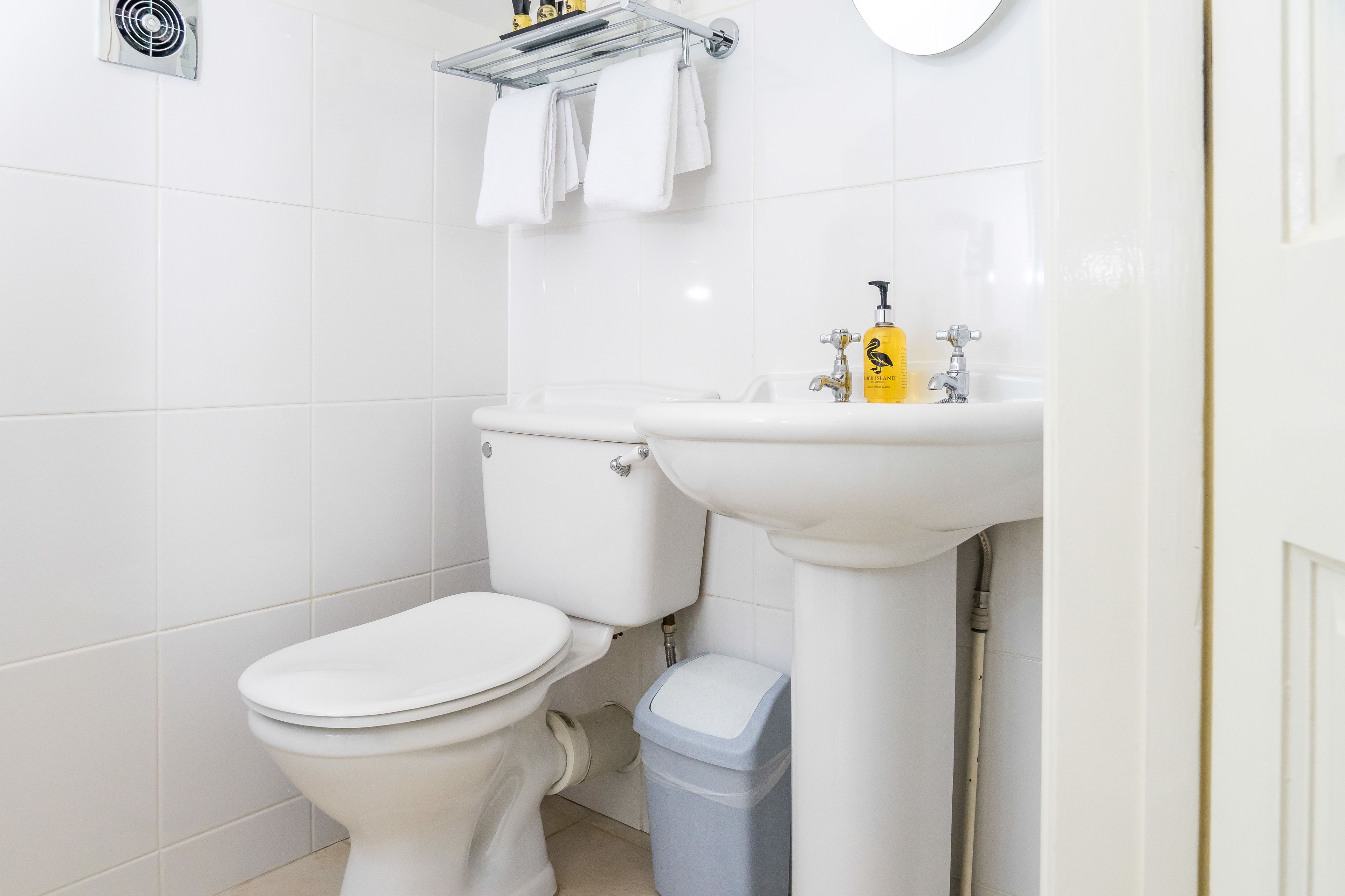 A modern bathroom with a toilet, sink, and trash bin.