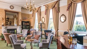 A traditional room with a fireplace, multiple armchairs, a bar area, and a large mirror.