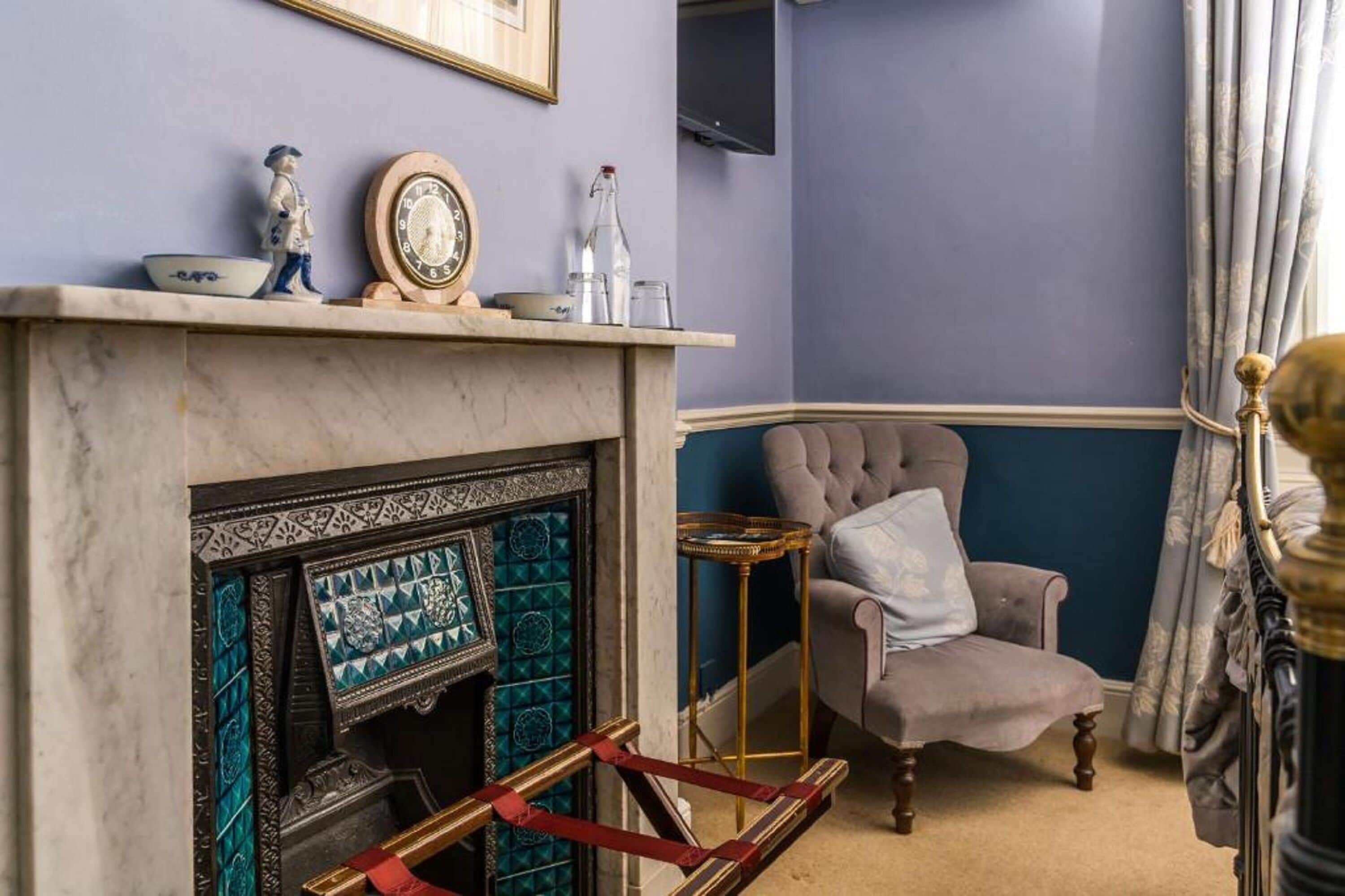 A room with a fireplace, a chair, a small table, and a television mounted on the wall.