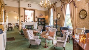A spacious living room with a fireplace, comfortable seating, and a large window with curtains.