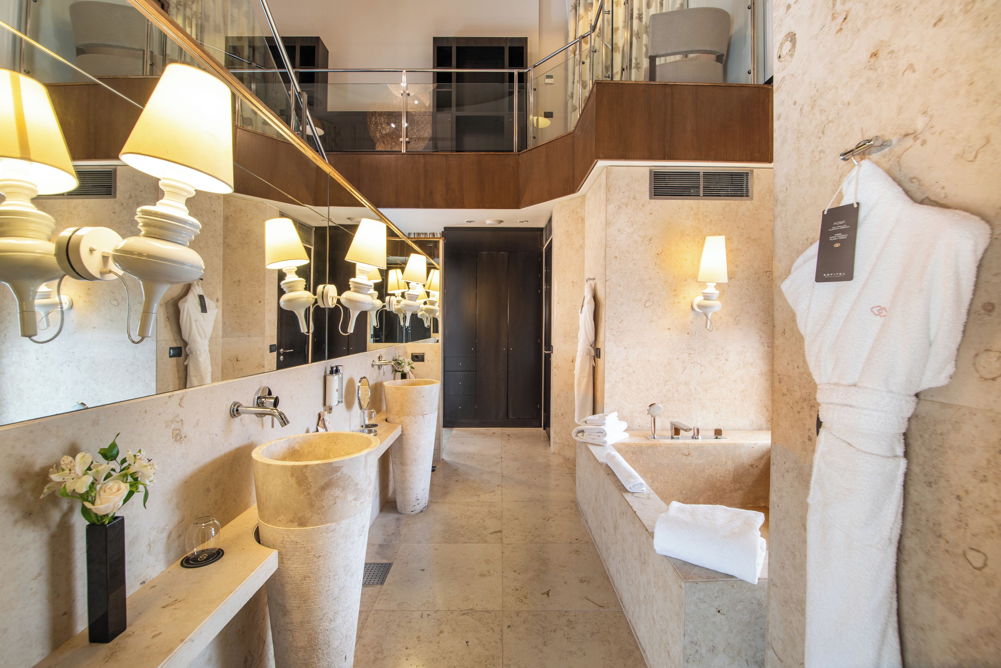 Un baño moderno con un espejo grande, varios lavamanos y una bañera.