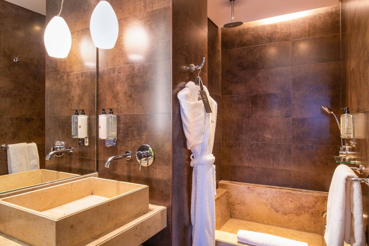 Une salle de bain moderne avec un grand lavabo rectangulaire, une douche à parois de verre et un porte-serviettes avec un peignoir.