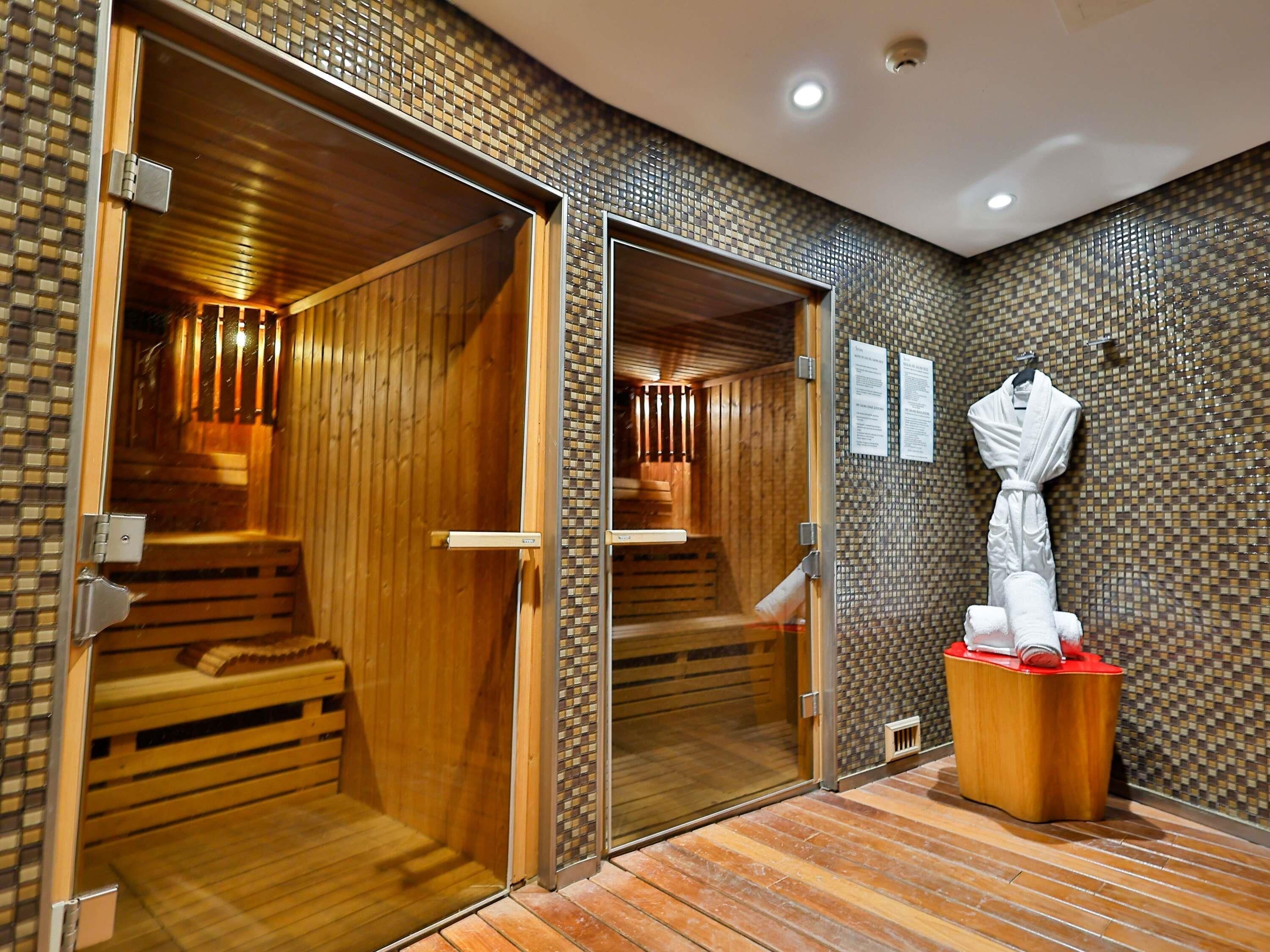 A sauna room with wooden benches and a tiled wall.