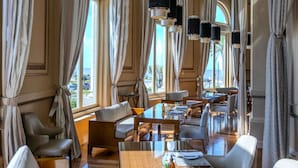 Un amplio comedor de hotel con techos altos, ventanas grandes y elegantes candelabros.